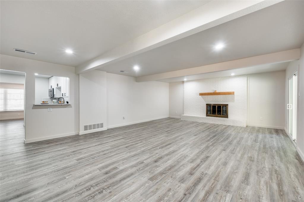 733 Southeast 3rd Street Grand Prairie, TX 75051 - Photo 6 of 24 Unfurnished living room featuring beamed ceiling, light wood-style floors, a fireplace, and recessed lighting