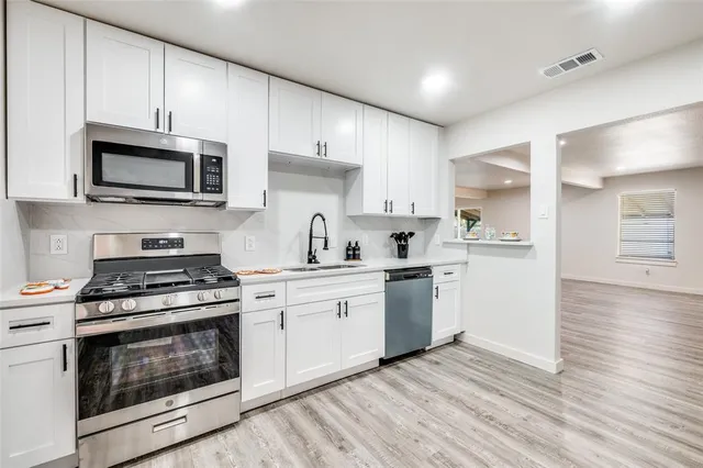 a kitchen with stainless steel appliances white cabinets white stove a sink and a microwave