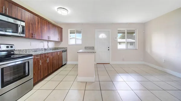 a kitchen with stainless steel appliances a sink a stove a microwave cabinets and a window