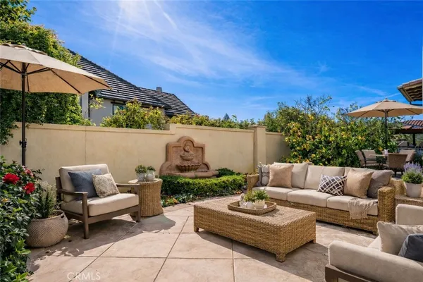 a view of a patio with couches table and chairs under an umbrella