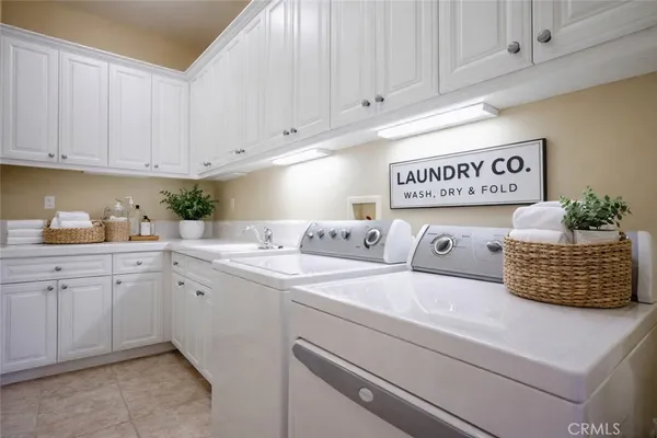 a utility room with stainless steel appliances granite countertop a sink and cabinets
