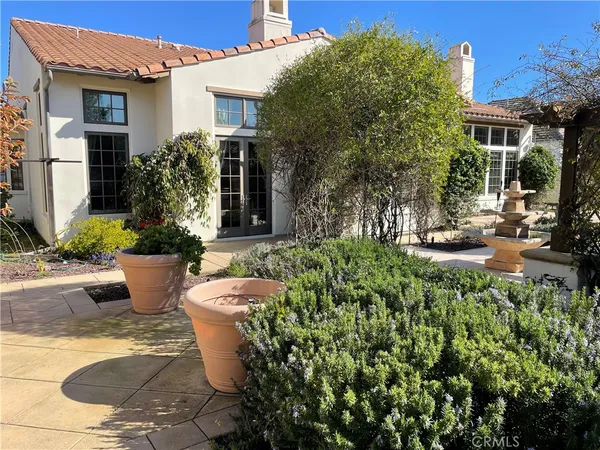 a view of a house with potted plants and a fountain