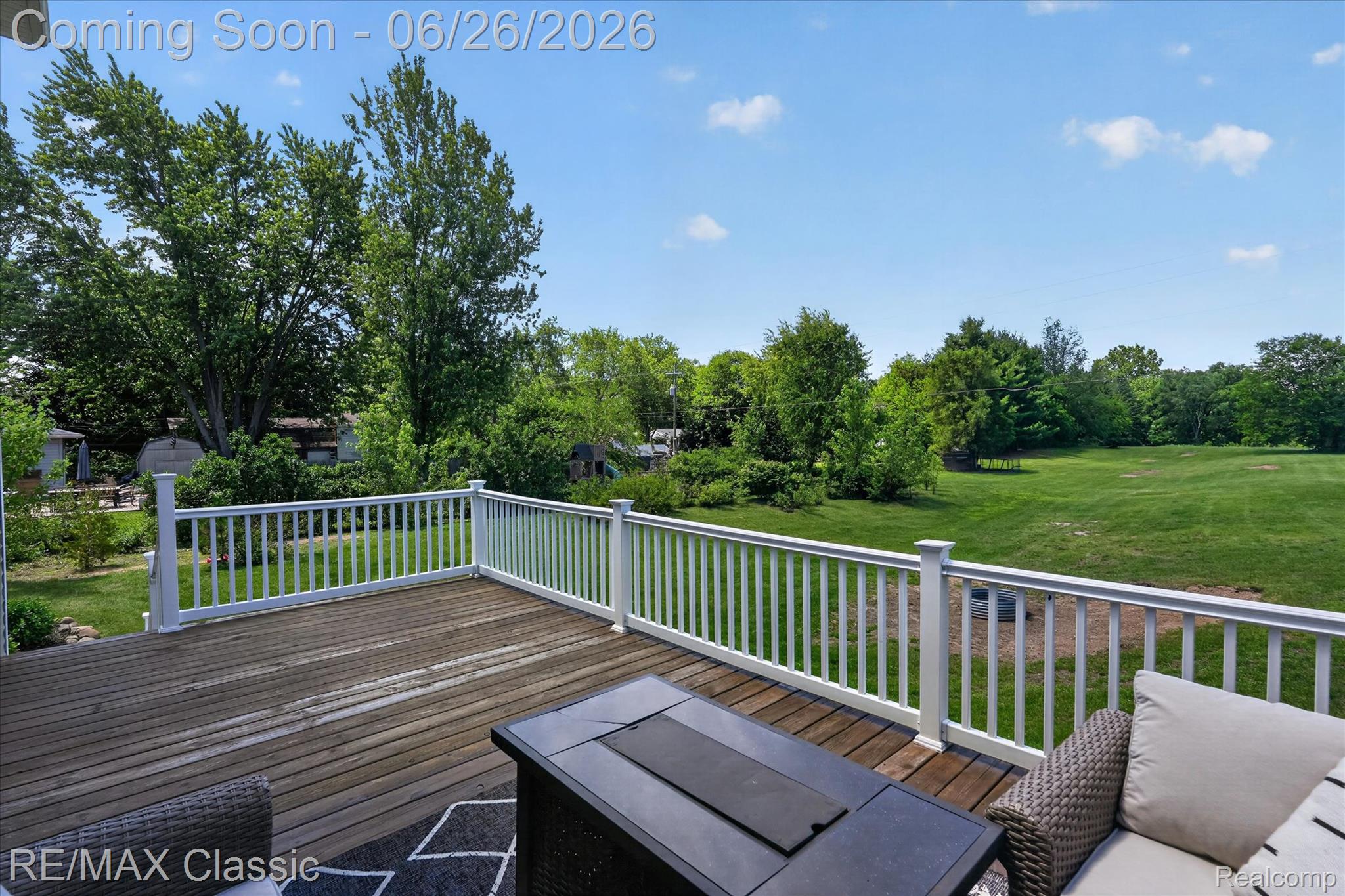3205 North Milford Road Highland, MI 48357 - Photo 42 of 53 Expansive wood deck with white railing overlooking mature trees and a substantial grassy area