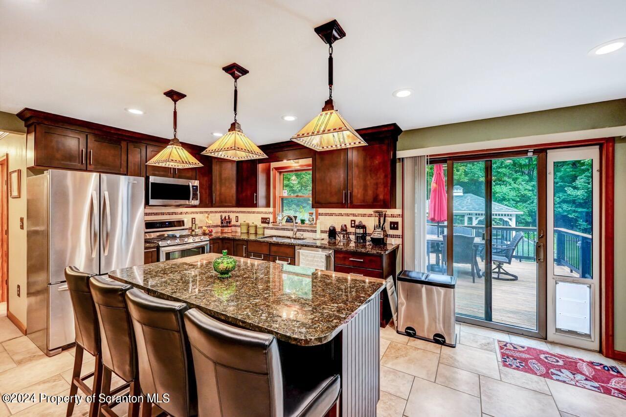 755 Spring Hill Road Sterling, PA 18463 - Photo 20 of 99 a kitchen with granite countertop kitchen island stainless steel appliances a dining table chairs sink and wooden floor