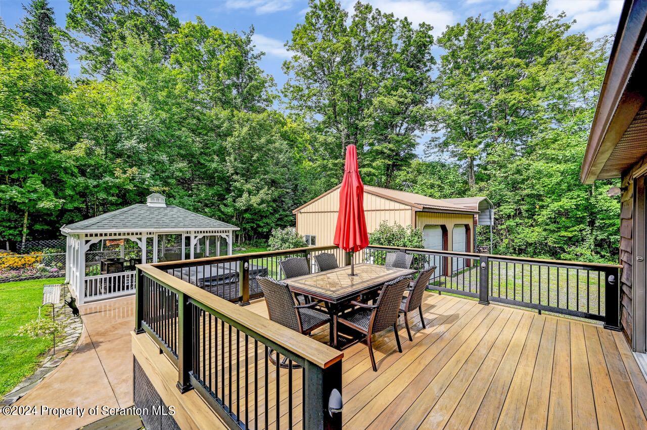 755 Spring Hill Road Sterling, PA 18463 - Photo 58 of 99 a view of a roof deck with table and chairs under an umbrella with wooden floor