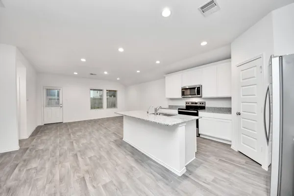 a view of kitchen with kitchen island wooden floor center island and stainless steel appliances