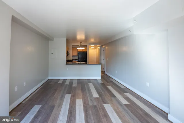 a view of a hallway with wooden floor and a kitchen space