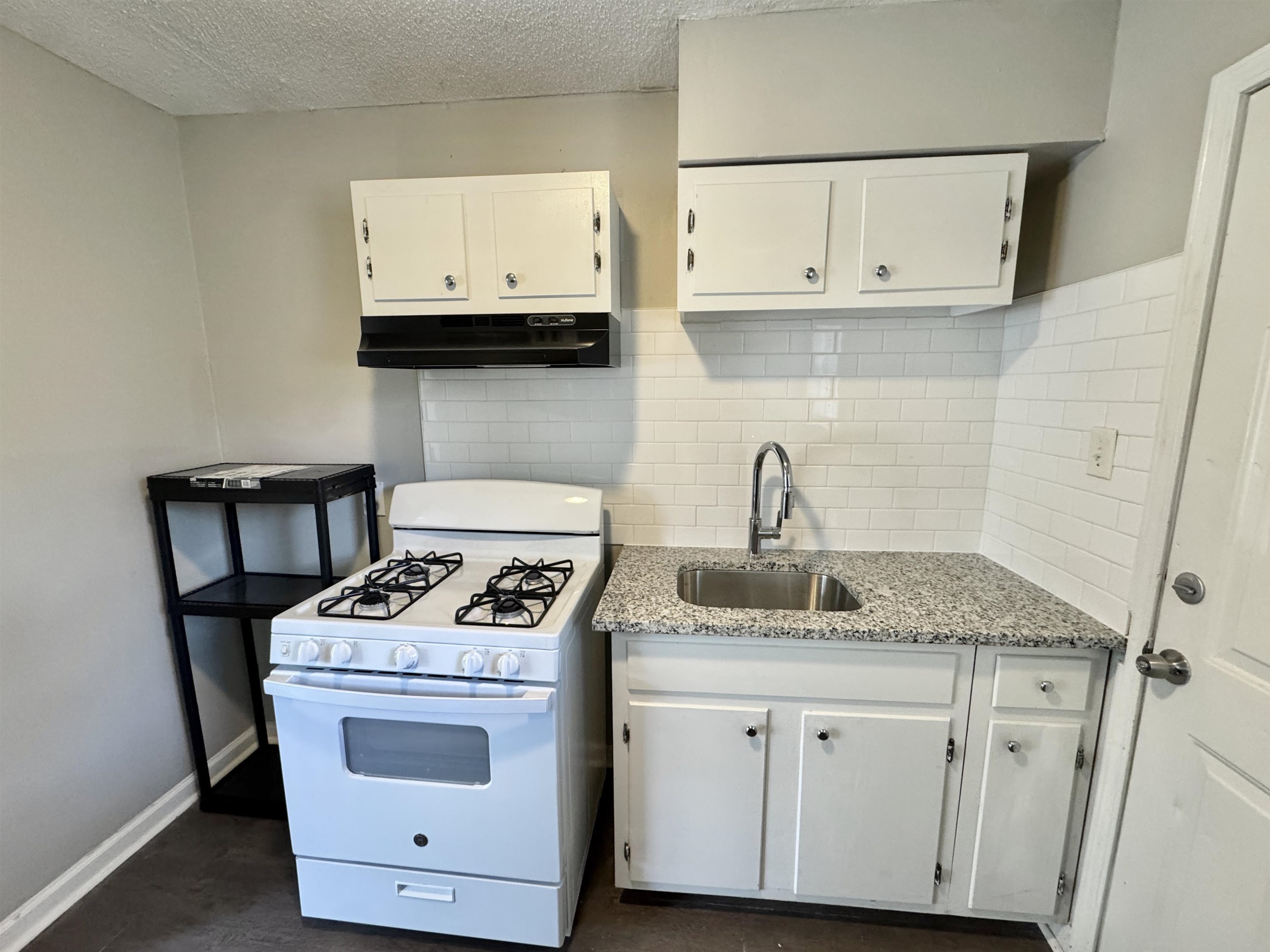 1825 Castalia Street Memphis, TN 38114 - Photo 25 of 30 a kitchen with granite countertop white cabinets and a stove with wooden floor