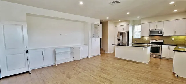 a kitchen with stainless steel appliances granite countertop a refrigerator sink and white cabinets