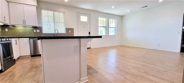 a view of a kitchen with fridge and wooden floor
