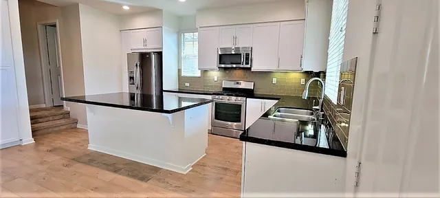 a kitchen with stainless steel appliances granite countertop a refrigerator and a stove