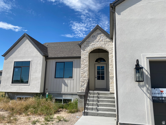 4676 West 75 North, Unit 401 West Point, UT 84015 - Photo 2 of 17 Exterior featuring a stone-clad entry arch and a paneled front door with an arched transom