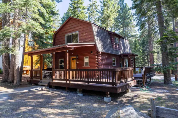 a view of a house with a wooden deck and furniture in a yard