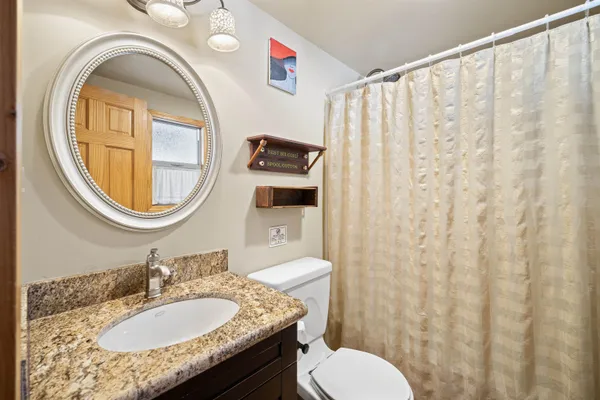 a bathroom with a granite countertop toilet sink and mirror