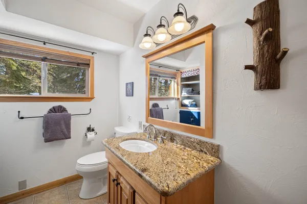 a bathroom with a granite countertop sink a toilet and mirror