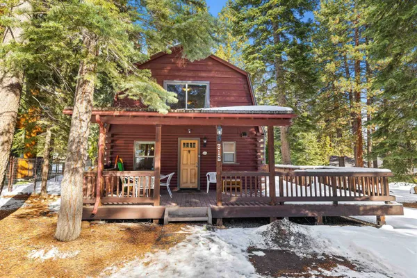 a view of a house with a wooden deck and a tree
