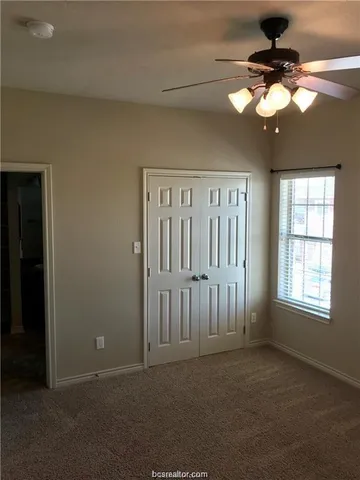 an empty room with windows and a chandelier fan