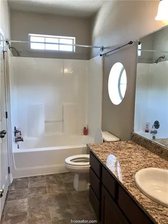 a bathroom with a granite countertop sink a toilet a mirror and bathtub