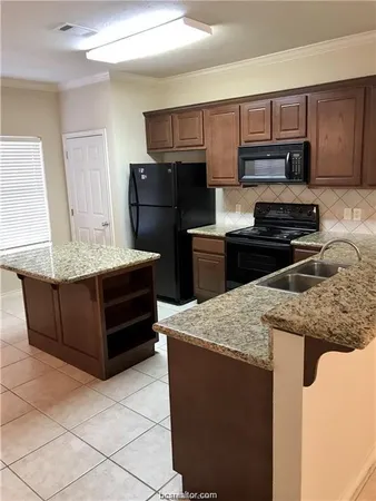 a kitchen with granite countertop a refrigerator a stove and wooden cabinets