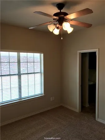 an empty room with windows and fan