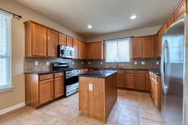 a large kitchen with stainless steel appliances granite countertop a stove sink and cabinets
