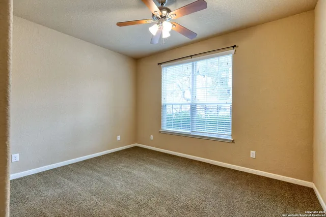 an empty room with a window and a fan