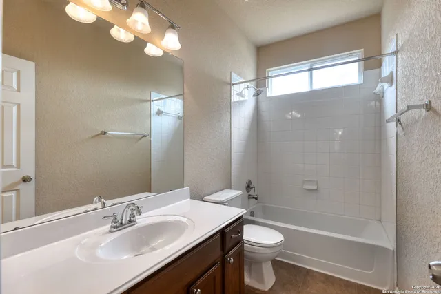 a bathroom with a sink a toilet a shower and a large mirror