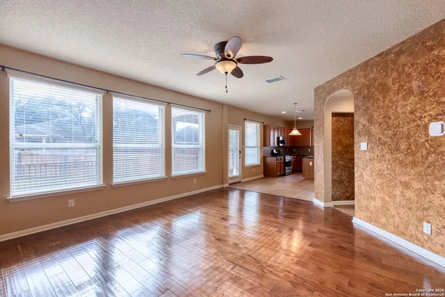 a view of empty room with wooden floor and fan