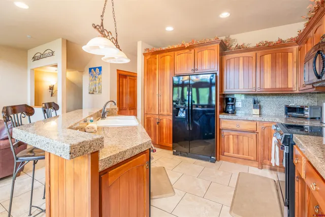 a kitchen with stainless steel appliances granite countertop a refrigerator a sink dishwasher a stove and a dining table with wooden floor