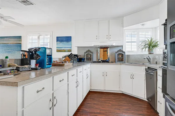 a kitchen with white cabinets a sink dishwasher and a stove with wooden floor