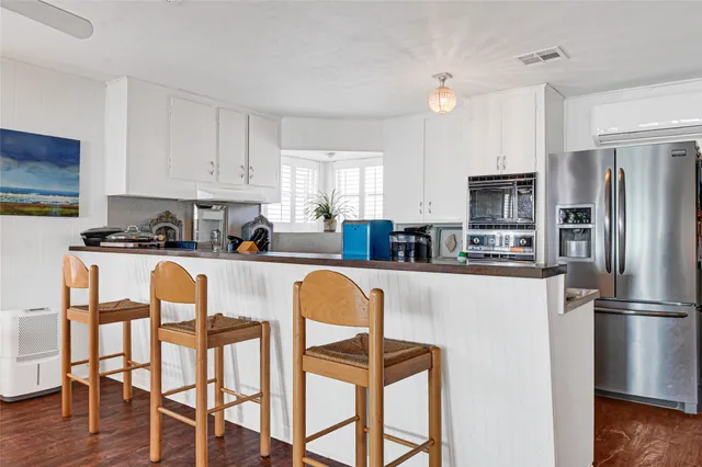 a kitchen with stainless steel appliances granite countertop a refrigerator a stove a sink dishwasher a dining table and chairs with wooden floor