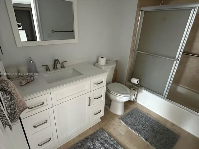 a bathroom with a granite countertop toilet sink and a mirror