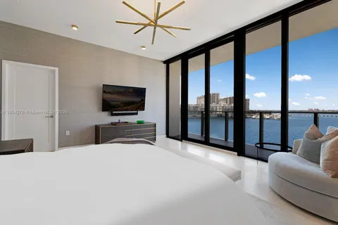 a bedroom with furniture a flat screen tv and a large window