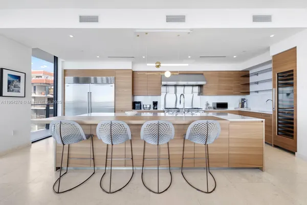 a kitchen with stainless steel appliances granite countertop a table chairs sink and cabinets