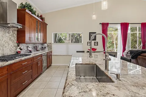 a large kitchen with stainless steel appliances granite countertop a sink stove and wooden cabinets