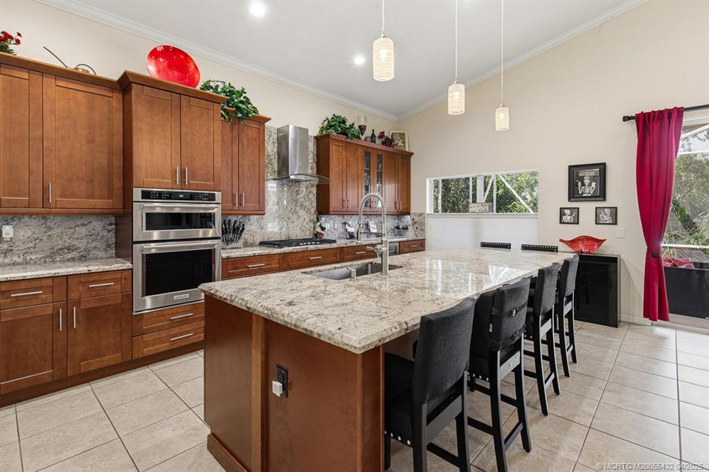 7213 Southeast Magellan Lane Stuart, FL 34997 - Photo 9 of 47 a kitchen with stainless steel appliances granite countertop a kitchen island a stove a sink a dining table and chairs with wooden floor