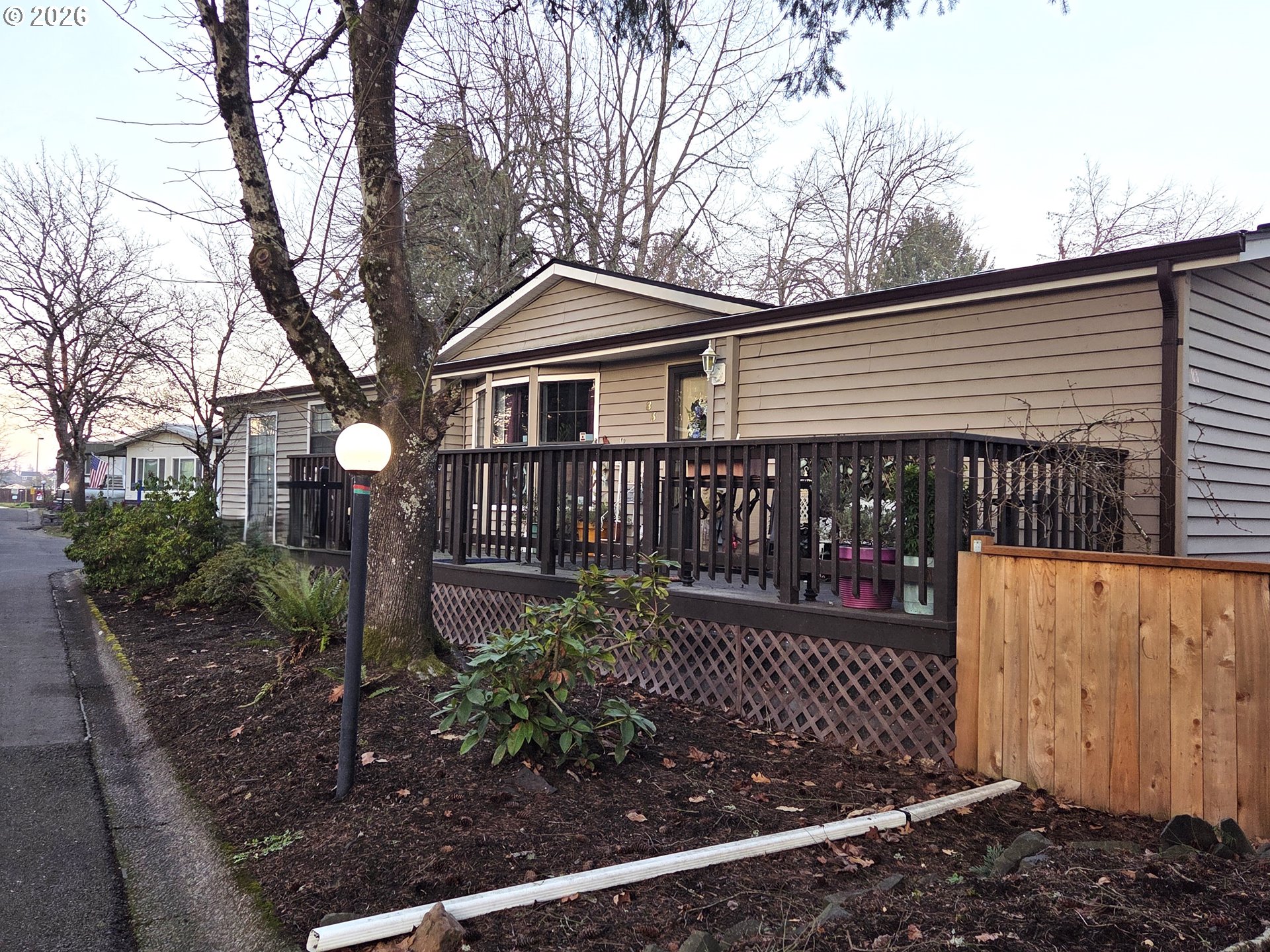 1475 Green Acres Road, Unit 83 Eugene, OR 97408 - Photo 29 of 37 a view of a brick house with a small yard and wooden fence and plants