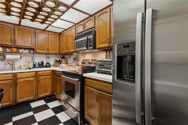 a kitchen with stainless steel appliances granite countertop a refrigerator a stove and a sink with wooden floor