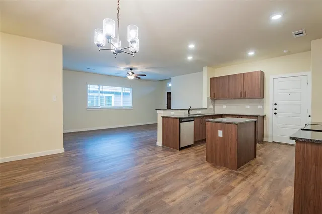 a kitchen with stainless steel appliances a stove top oven a sink a refrigerator white cabinets and wooden floor