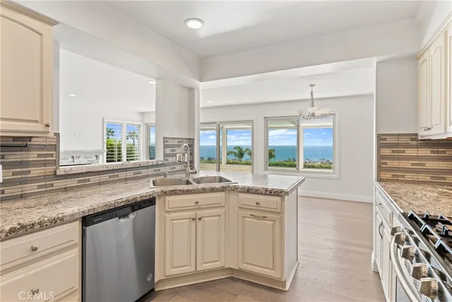 a kitchen with granite countertop white cabinets stainless steel appliances and a window