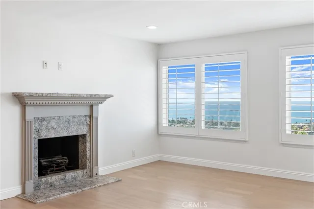a view of an empty room with wooden floor and a kitchen