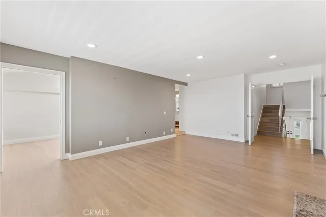 a view of an empty room with wooden floor and a fireplace