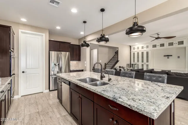 a kitchen with stainless steel appliances granite countertop a sink a refrigerator and a wooden floors