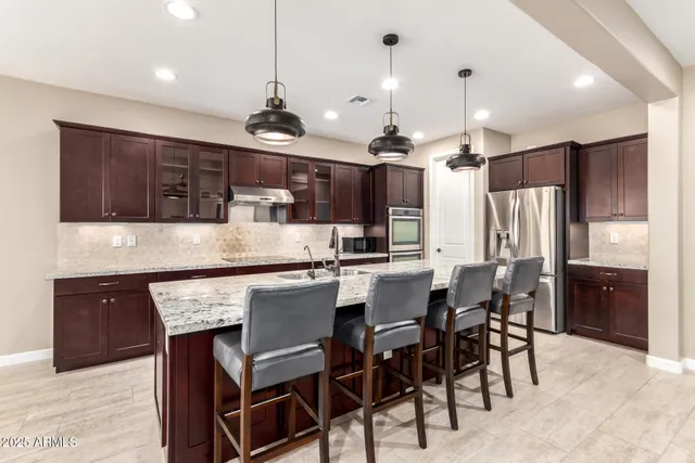 a kitchen with stainless steel appliances kitchen island granite countertop a table chairs sink and cabinets