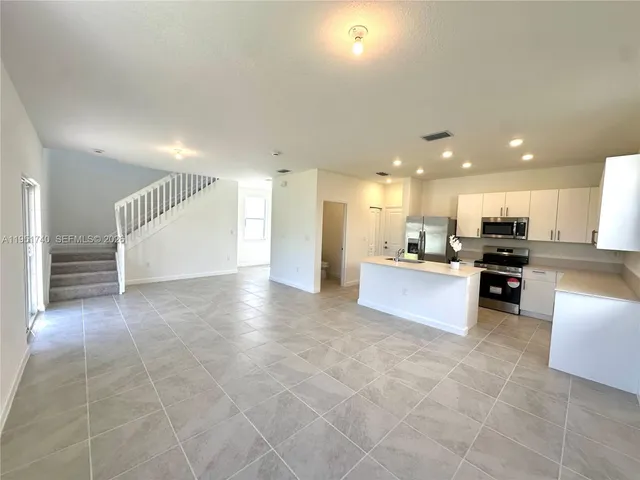 a view of kitchen with kitchen island granite countertop a stove a sink a refrigerator and a counter top space