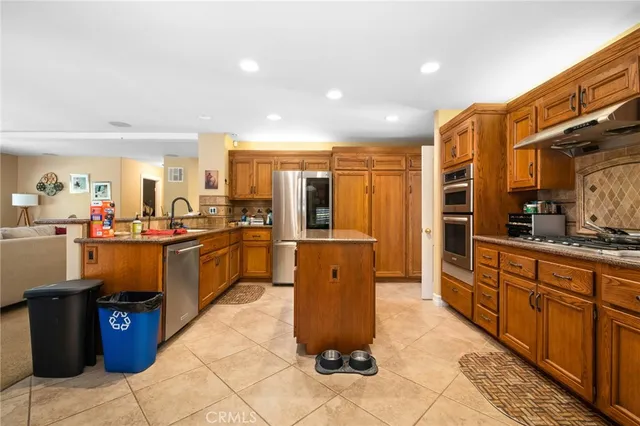 a large kitchen with stainless steel appliances kitchen island granite countertop a refrigerator and a sink
