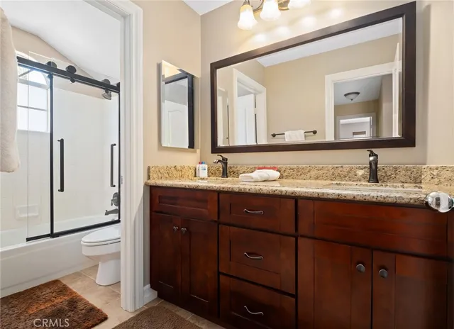 a bathroom with a granite countertop sink toilet and mirror