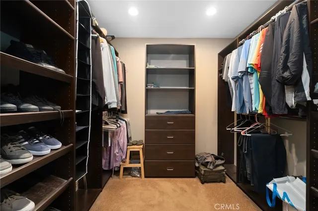 a view of walk in closet with clothes and shoes