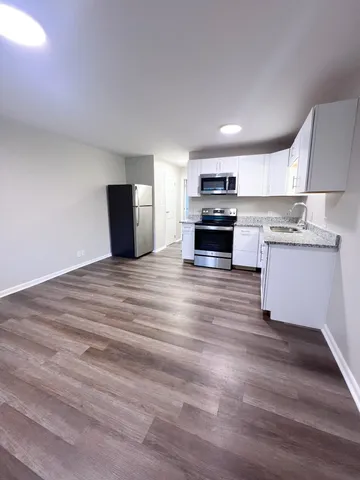 a kitchen with stainless steel appliances wooden floor and a refrigerator