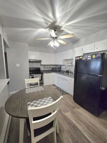 a kitchen with granite countertop stainless steel appliances a refrigerator a stove top oven a sink a dining table and chairs